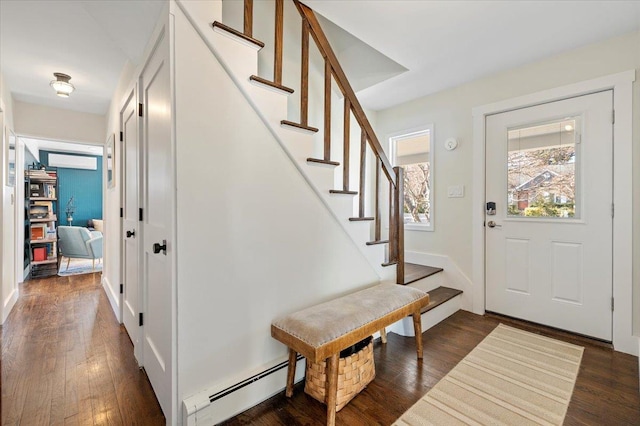 foyer with stairs, baseboard heating, and dark wood-style flooring