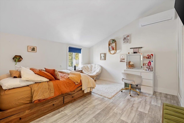 bedroom with a wall mounted air conditioner, vaulted ceiling, baseboards, and wood finished floors