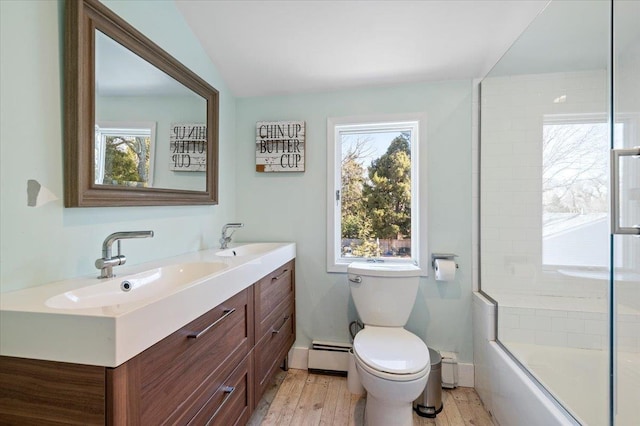 full bath with a baseboard radiator, a healthy amount of sunlight, toilet, and wood finished floors