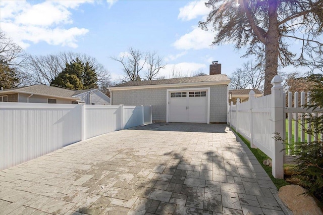 garage with decorative driveway and fence