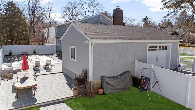 view of property exterior with a fenced backyard, a chimney, a shingled roof, and a patio