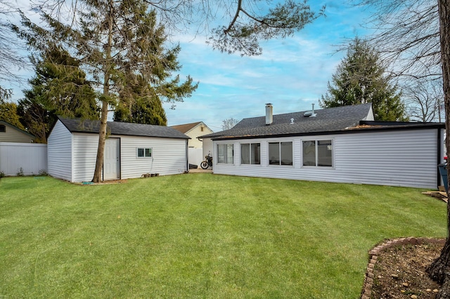 rear view of house featuring a yard, a chimney, a storage unit, fence, and an outdoor structure