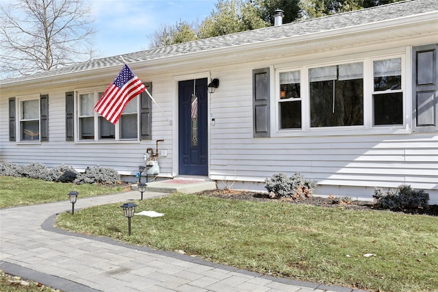 view of front of home featuring roof with shingles and a front lawn