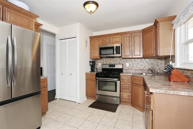 kitchen with light tile patterned floors, appliances with stainless steel finishes, decorative backsplash, and a sink