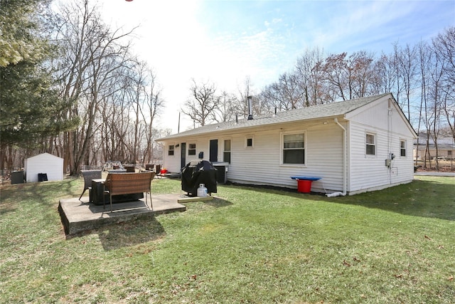 back of property with a yard, a shingled roof, and a patio area