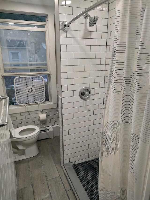 full bathroom featuring toilet, baseboard heating, cooling unit, wood finish floors, and a shower stall