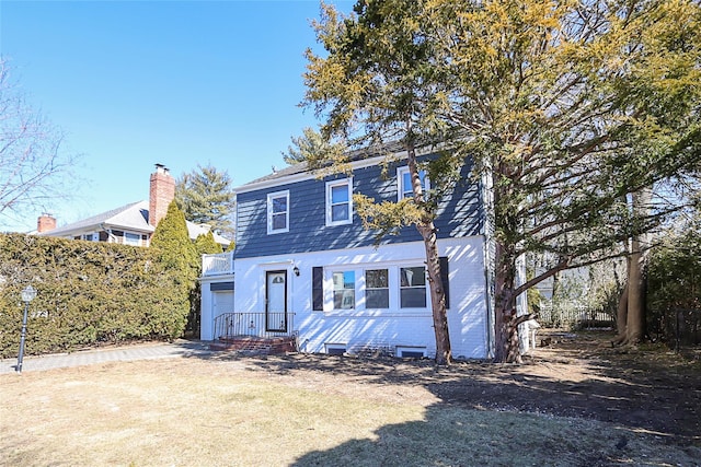 colonial home featuring a garage, driveway, brick siding, and fence