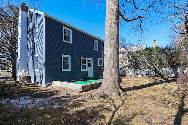 rear view of house featuring a chimney and fence