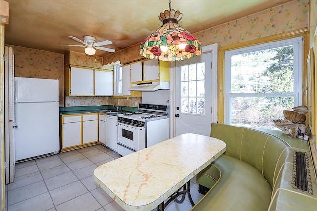 kitchen with white appliances, white cabinets, under cabinet range hood, and wallpapered walls