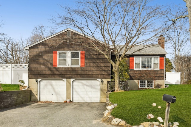 view of front facade featuring driveway, a chimney, an attached garage, fence, and a front lawn