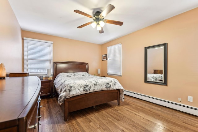 bedroom featuring ceiling fan, baseboard heating, and wood finished floors