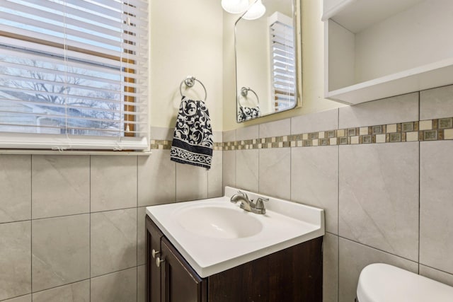 bathroom featuring toilet, tile walls, and vanity