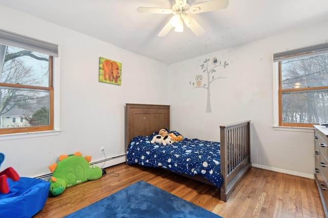 bedroom featuring a ceiling fan, a baseboard radiator, baseboards, and light wood finished floors