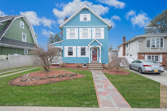 view of front facade with a front yard, concrete driveway, and fence