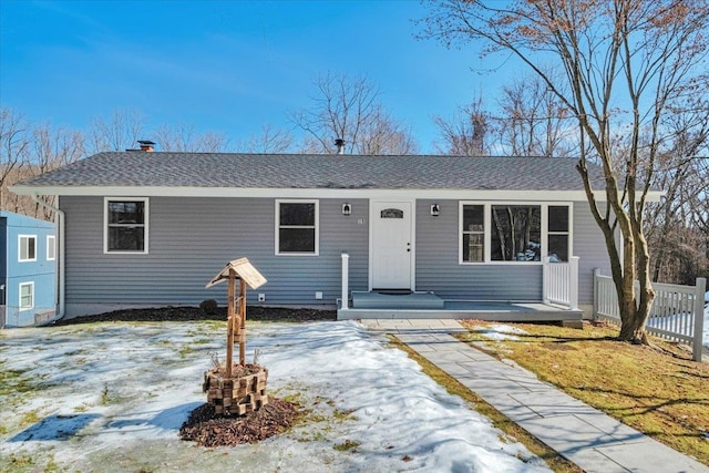 ranch-style home featuring fence and roof with shingles