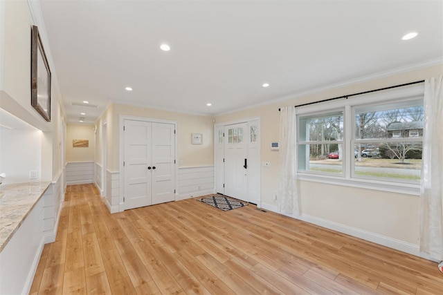 foyer with a wainscoted wall, light wood finished floors, recessed lighting, and crown molding