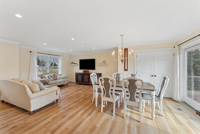 dining room with light wood-style floors, plenty of natural light, a chandelier, and ornamental molding