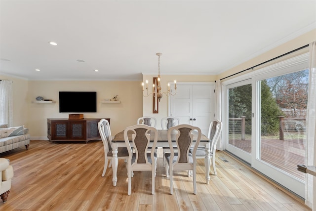 dining space with crown molding, light wood-type flooring, a notable chandelier, and baseboards