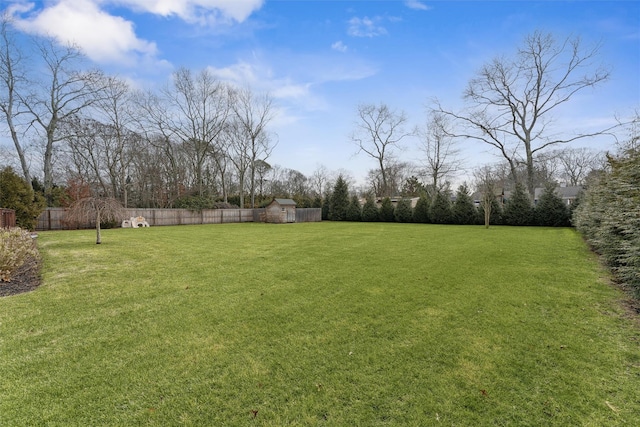 view of yard featuring a storage unit and fence