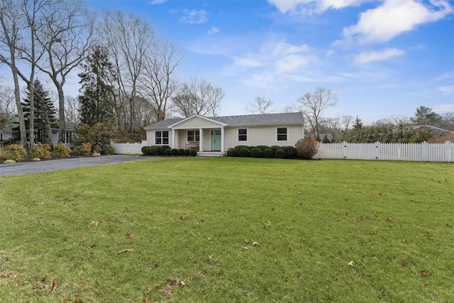 ranch-style home with aphalt driveway, fence, and a front lawn