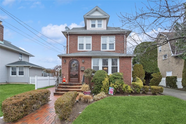 traditional style home with brick siding, fence, and a front lawn