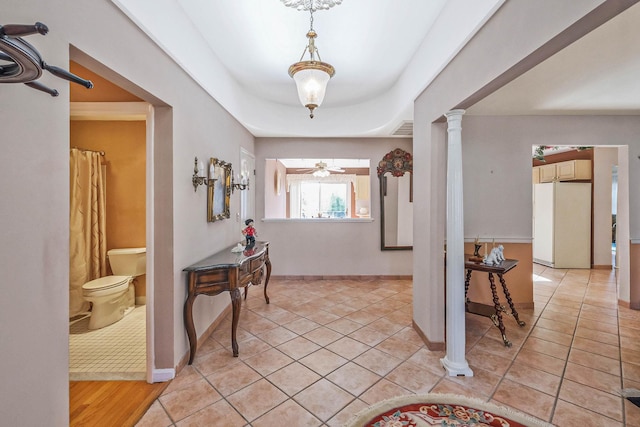 foyer with light tile patterned floors, decorative columns, and baseboards