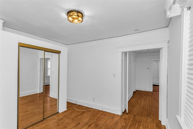 interior space with baseboard heating, a closet, baseboards, and hardwood / wood-style flooring