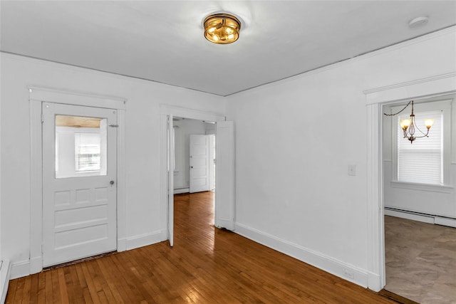 spare room featuring baseboards, baseboard heating, hardwood / wood-style floors, and a chandelier