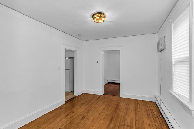 spare room featuring hardwood / wood-style flooring, baseboards, and a baseboard heating unit