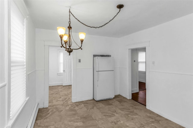 unfurnished dining area featuring a chandelier, a baseboard radiator, and baseboards