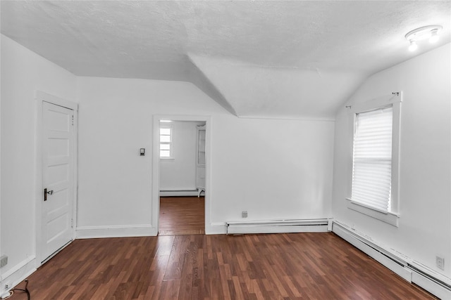 additional living space with vaulted ceiling, a baseboard heating unit, baseboard heating, and wood finished floors