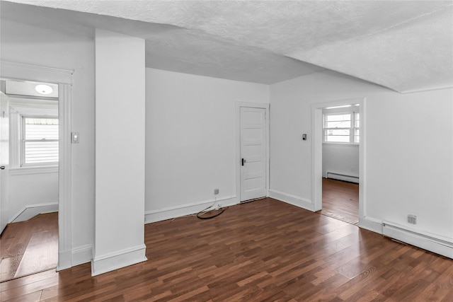 spare room featuring plenty of natural light, a baseboard radiator, a textured ceiling, and wood finished floors