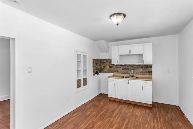 kitchen with dark wood-style flooring, a sink, white cabinetry, light countertops, and decorative backsplash