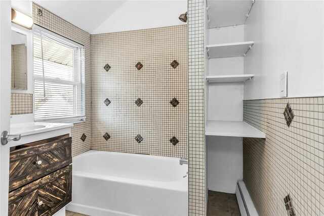 bathroom featuring tile walls, shower / bathtub combination, lofted ceiling, a baseboard radiator, and vanity