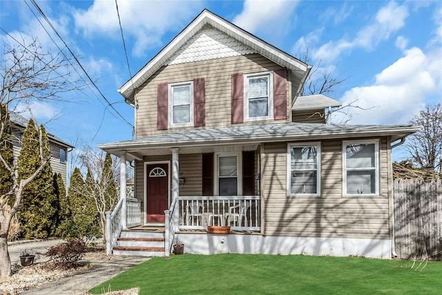 view of front of house featuring a porch, fence, and a front lawn