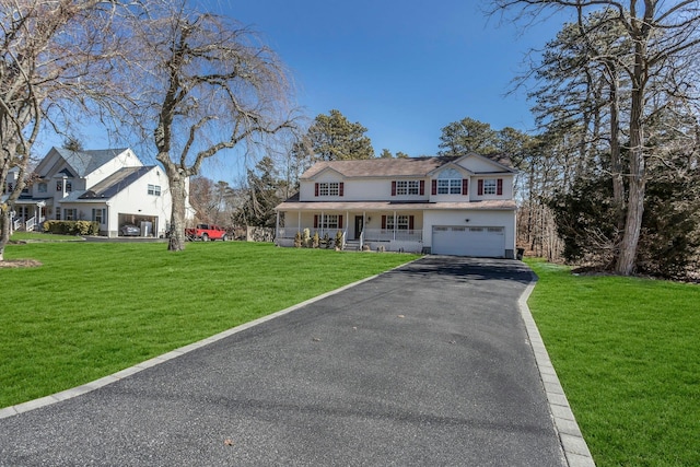 view of front facade featuring an attached garage, covered porch, driveway, and a front lawn