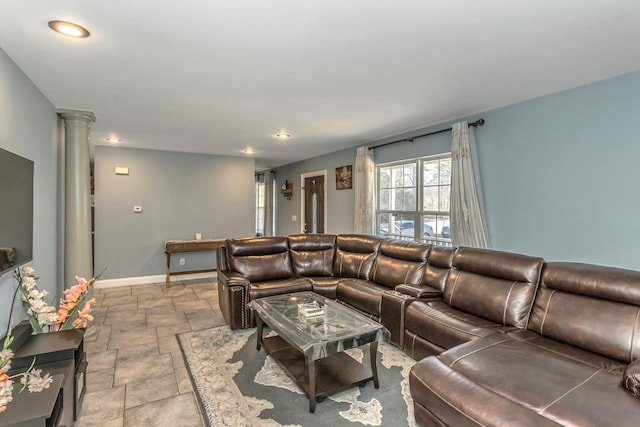 living area featuring ornate columns, stone tile floors, baseboards, and recessed lighting