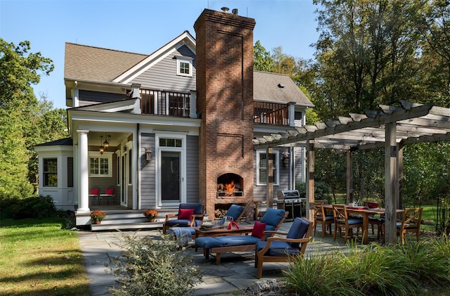 back of house featuring an outdoor brick fireplace, a patio area, a balcony, and a pergola