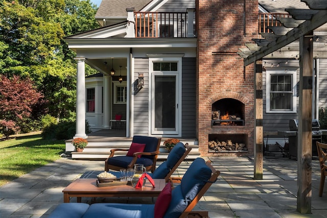 view of patio / terrace with an outdoor brick fireplace, a balcony, and a pergola