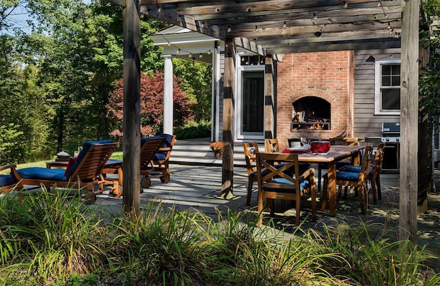 view of patio / terrace featuring an outdoor brick fireplace, outdoor dining space, and a pergola