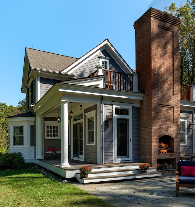 rear view of house with a balcony, a shingled roof, a fireplace, and a chimney