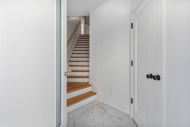 staircase with marble finish floor and baseboards