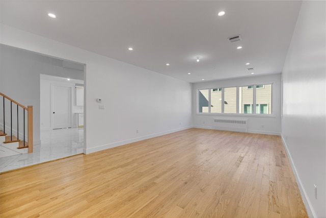 unfurnished living room featuring visible vents, radiator heating unit, light wood-style flooring, stairs, and recessed lighting