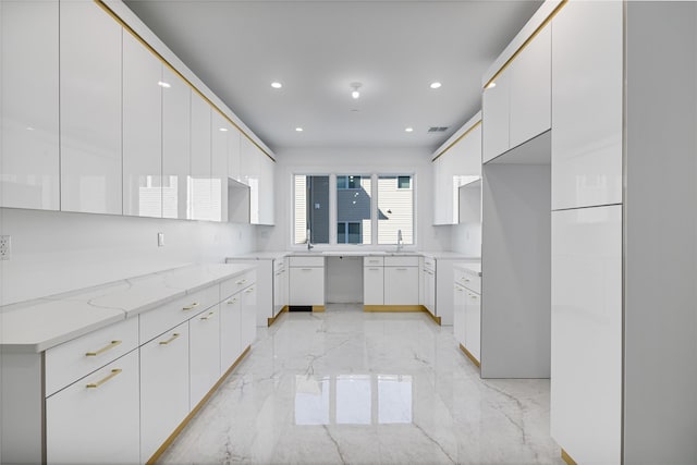 kitchen with marble finish floor, recessed lighting, light stone countertops, a sink, and modern cabinets