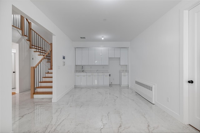 interior space with marble finish floor, radiator, stairway, a sink, and baseboards