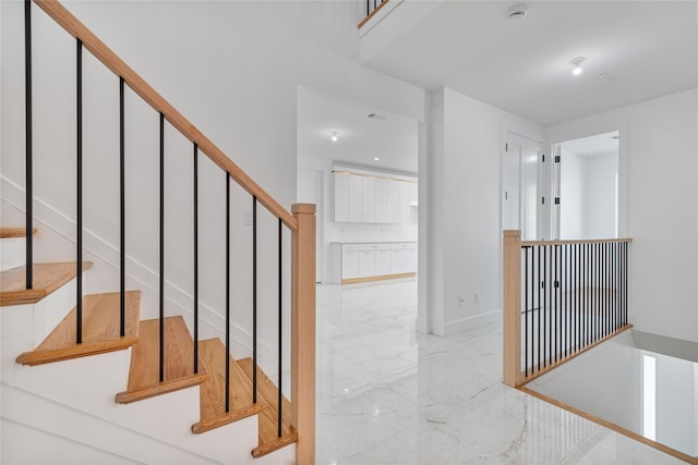 stairway with marble finish floor and baseboards