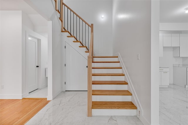 staircase with marble finish floor and baseboards