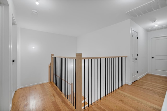 corridor with light wood finished floors, visible vents, and baseboards