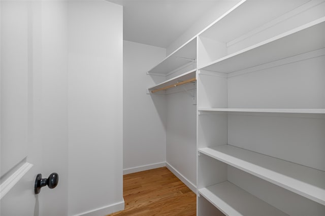 walk in closet with light wood-style floors