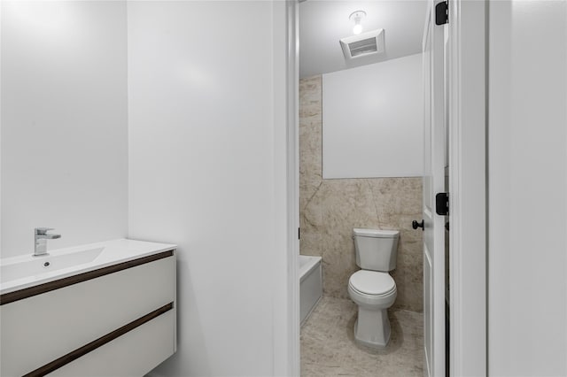 full bathroom with toilet, vanity, visible vents, tile walls, and tile patterned floors